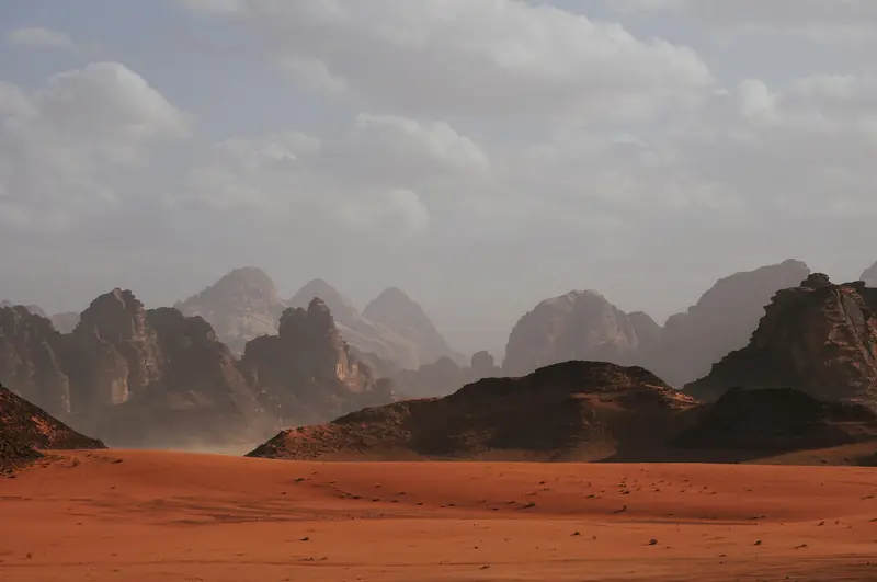 Red desert dunes under a soft sky
