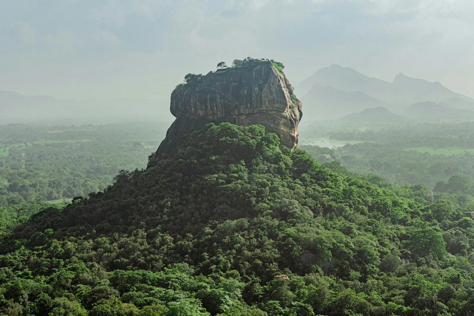 Sigiriya rock fortress rising above misty green jungle in Sri Lanka