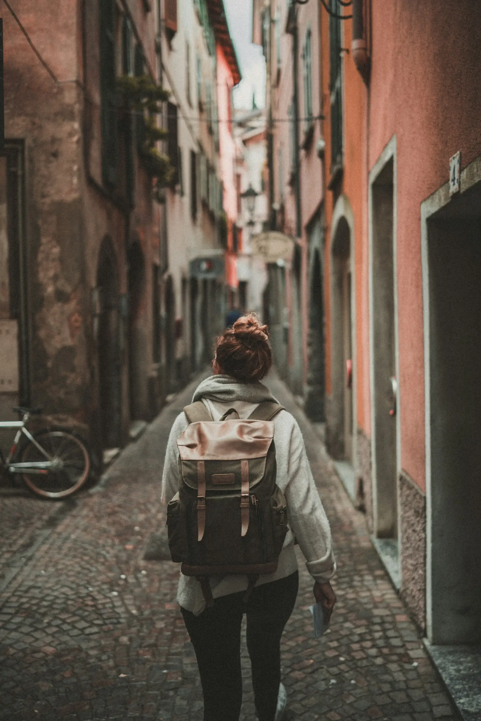 A traveller with a backpack walking down a narrow old-town lane