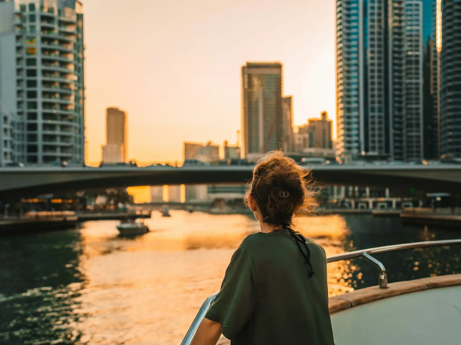 A traveller on a boat looking at the Dubai Marina skyline at sunset