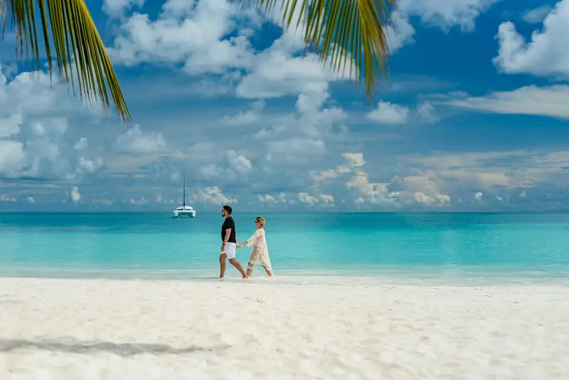 A couple walking along a white sand beach in the Maldives
