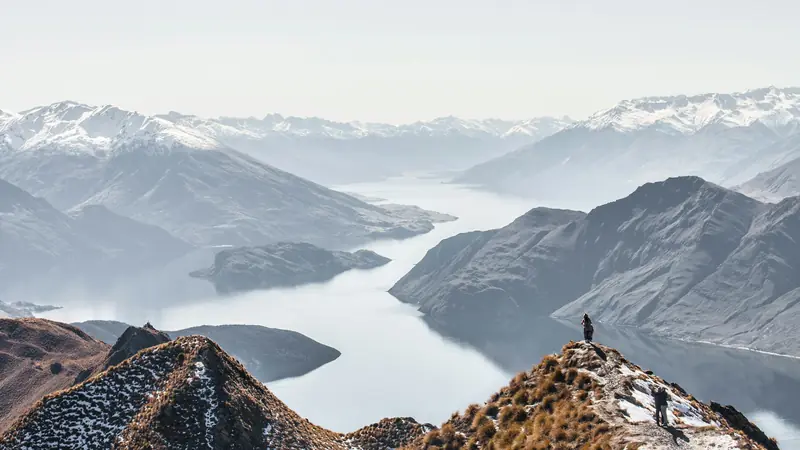 Hikers on a mountain lookout above a lake in New Zealand